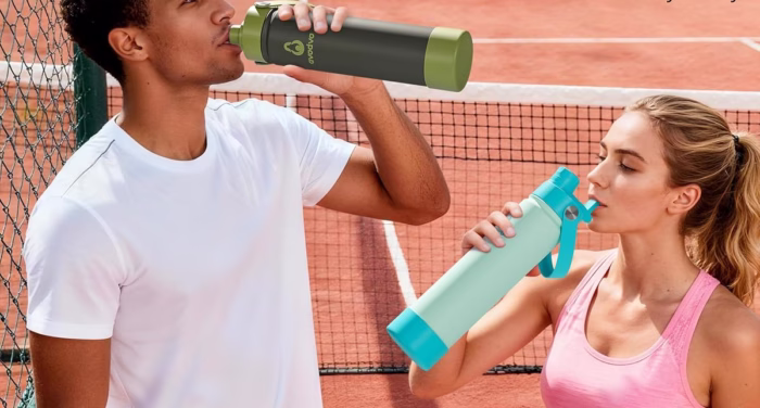 People drinking water after playing tennis outdoors.