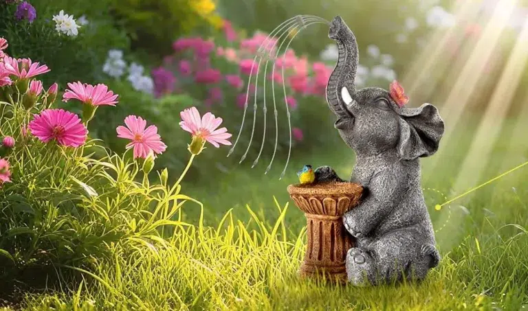 Elephant statue with flowers and sunlight in garden.