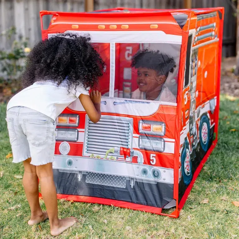 Kids playing in fire truck playhouse outside