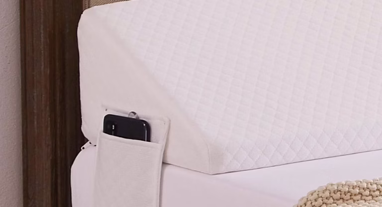 Foam wedge pillow with phone pocket on bed.