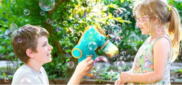 Children playing with bubble machine outdoors.