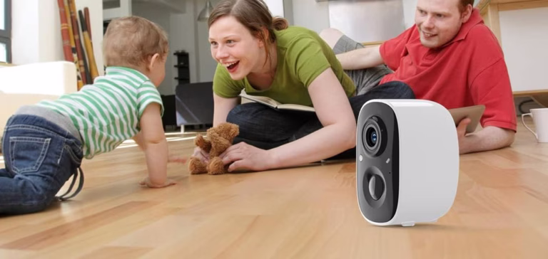 Parents and baby near smart camera on floor.
