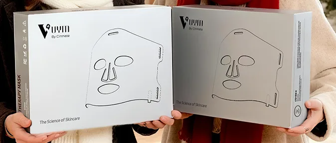 Two skincare face mask boxes held by people.
