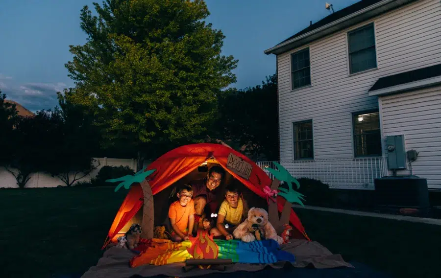 Family camping in backyard tent at night.