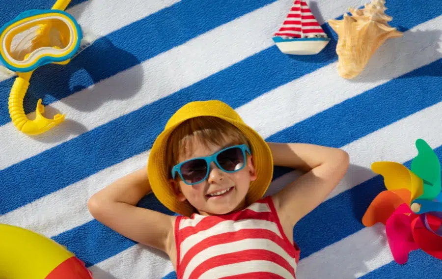 Child smiling on towel with beach toys