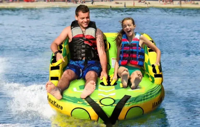 Two people tubing on water with life vests.