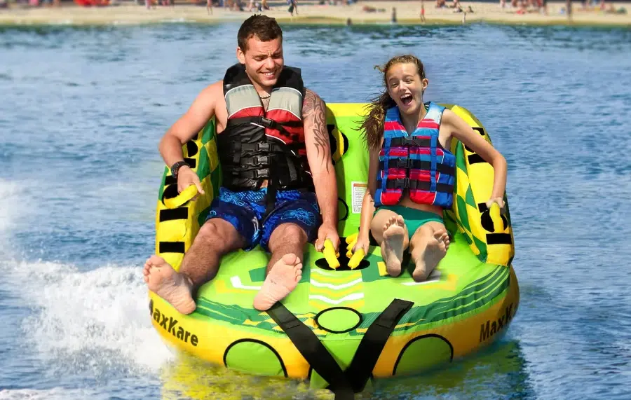 Two people tubing on water with life vests.