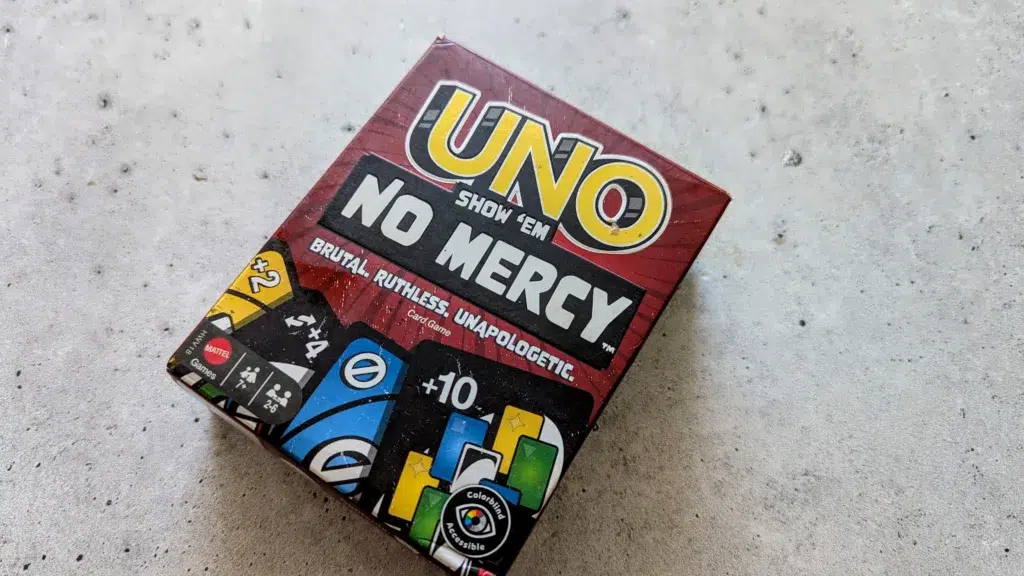UNO No Mercy card game box on concrete surface.