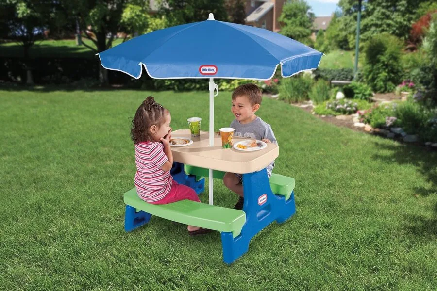 Kids at picnic table with umbrella in garden