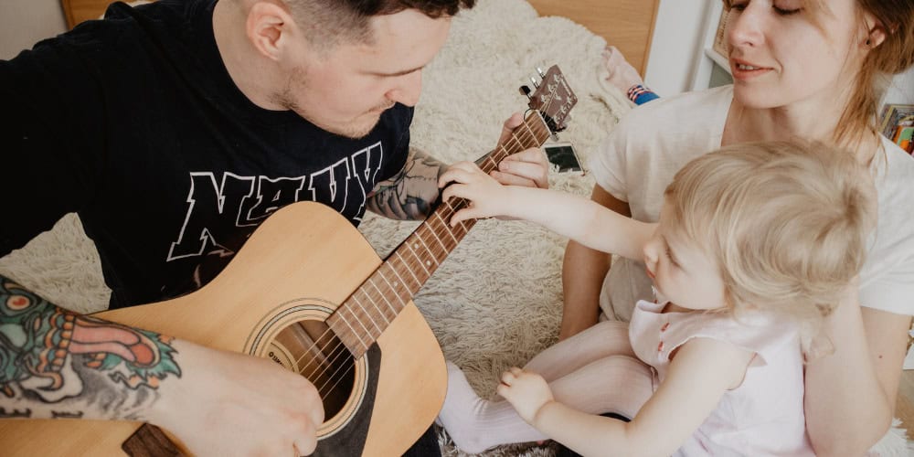 family learning to play guitar