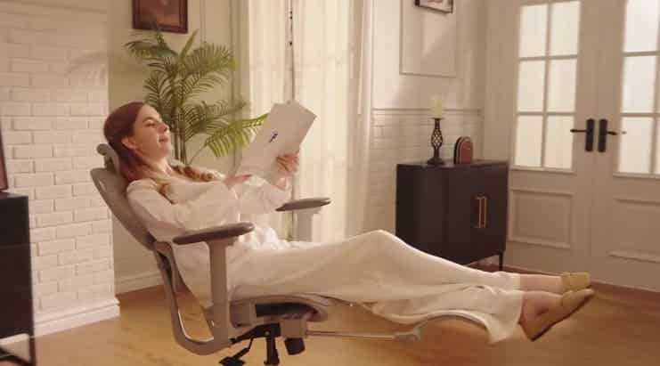 Woman reclining in chair reading document indoors