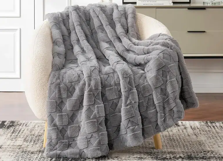 Gray textured blanket on beige armchair.