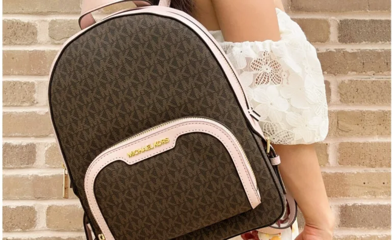 Woman holding Michael Kors backpack against brick wall.