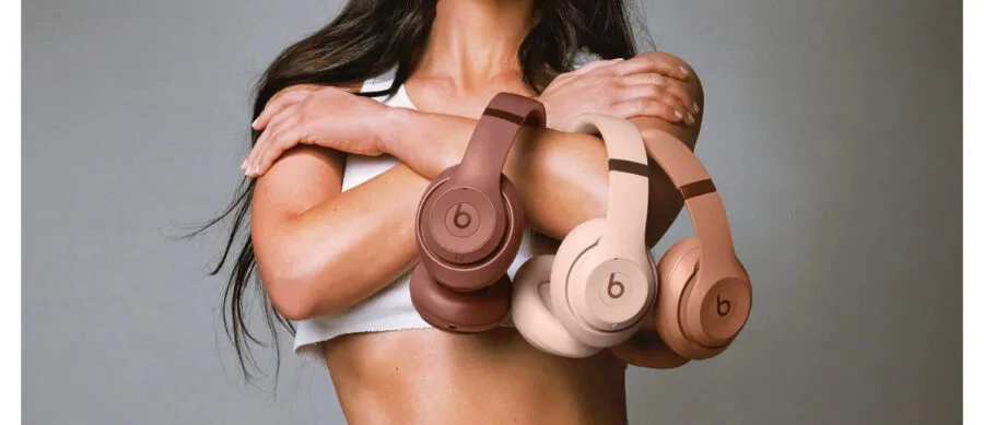 Woman displaying Beats headphones in three colors.