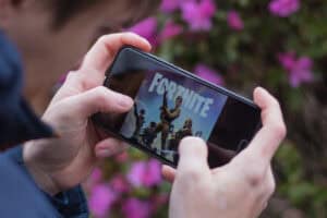 A person holding a cell phone with a fortnite game on it