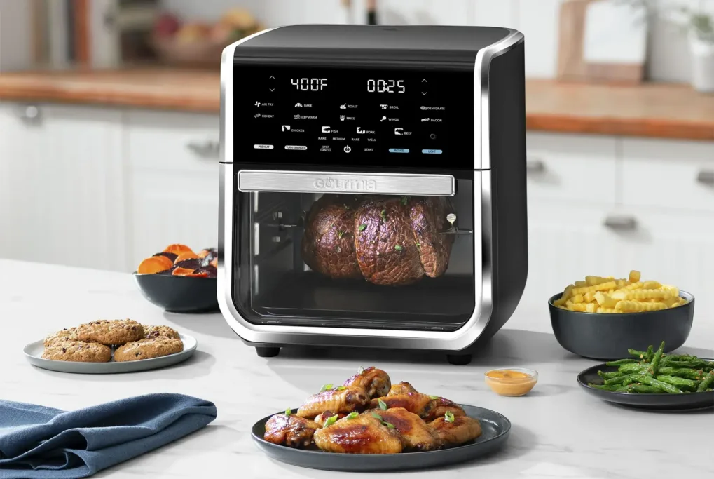Air fryer cooking roast with sides on countertop.