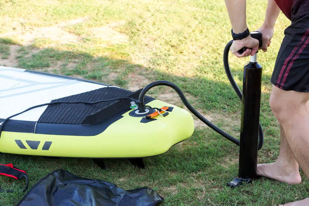 man putting air into inflatable stand up paddle board