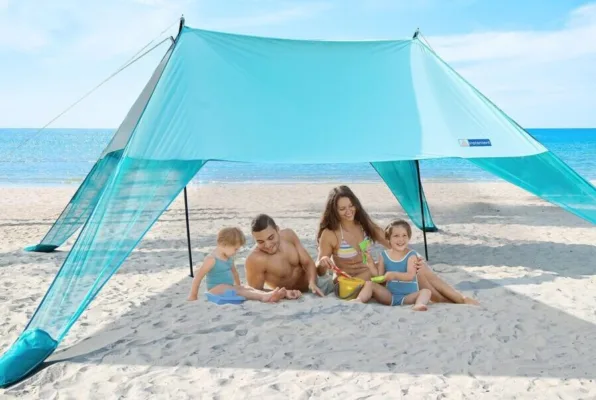 Family relaxing under beach canopy by the sea.
