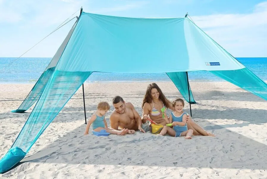 Family relaxing under beach canopy by the sea.