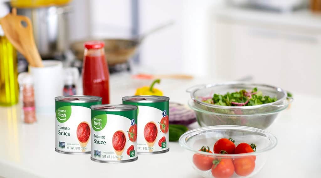 Tomato sauce cans with fresh vegetables on kitchen counter