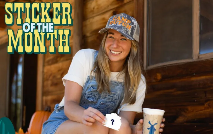 Smiling person with sticker and drink outdoors.