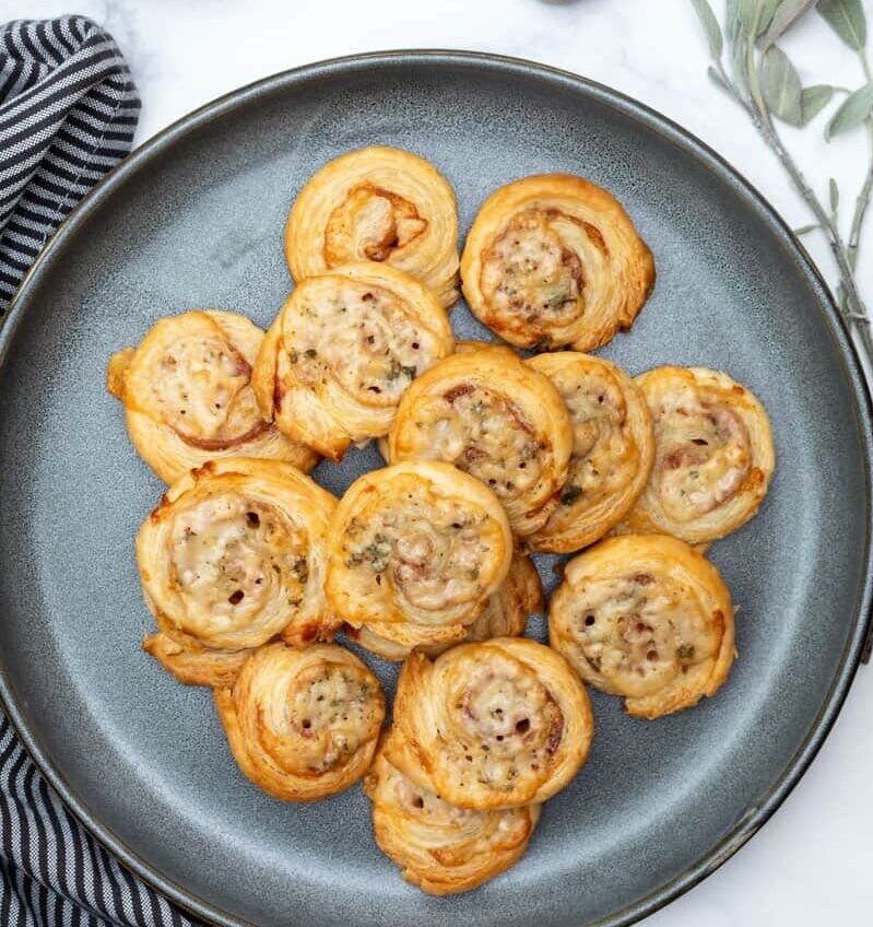 puff pastry pinwheels on plate with cutting board