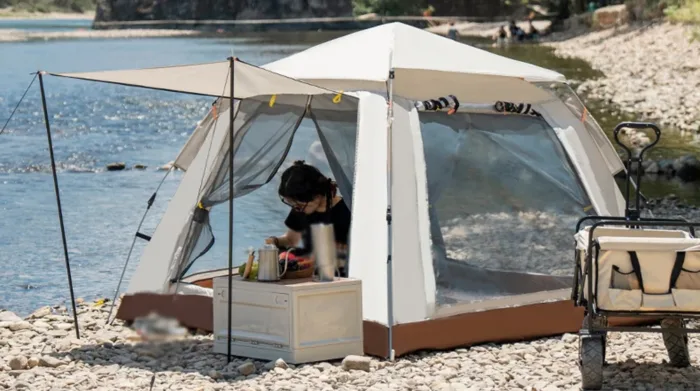 Person camping by a river with a tent.
