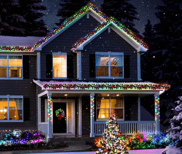 House with colorful Christmas lights in snow.