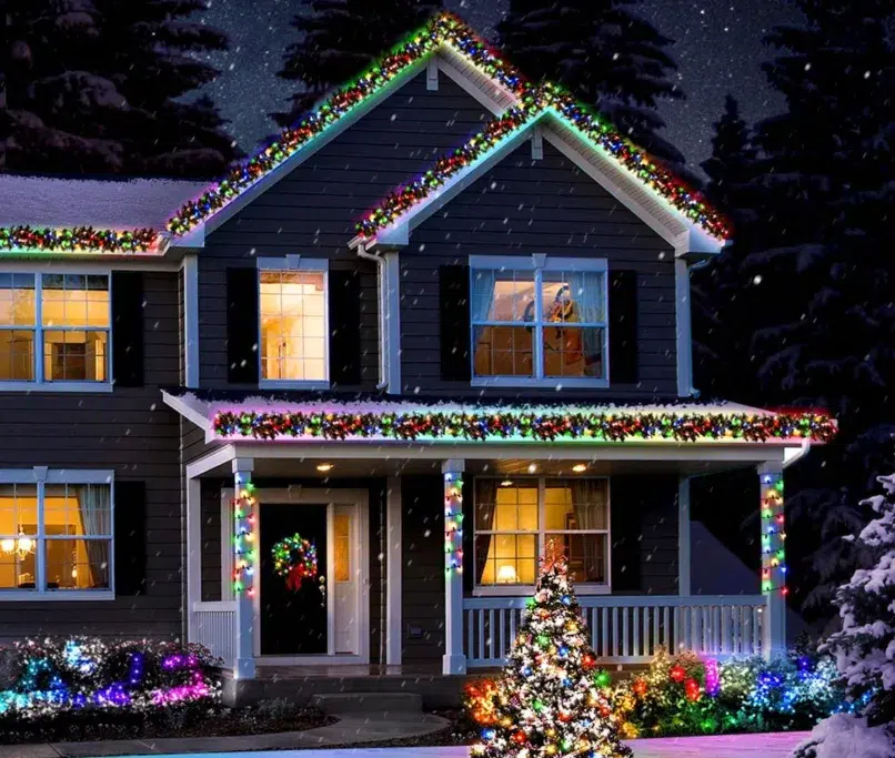House with colorful Christmas lights in snow.