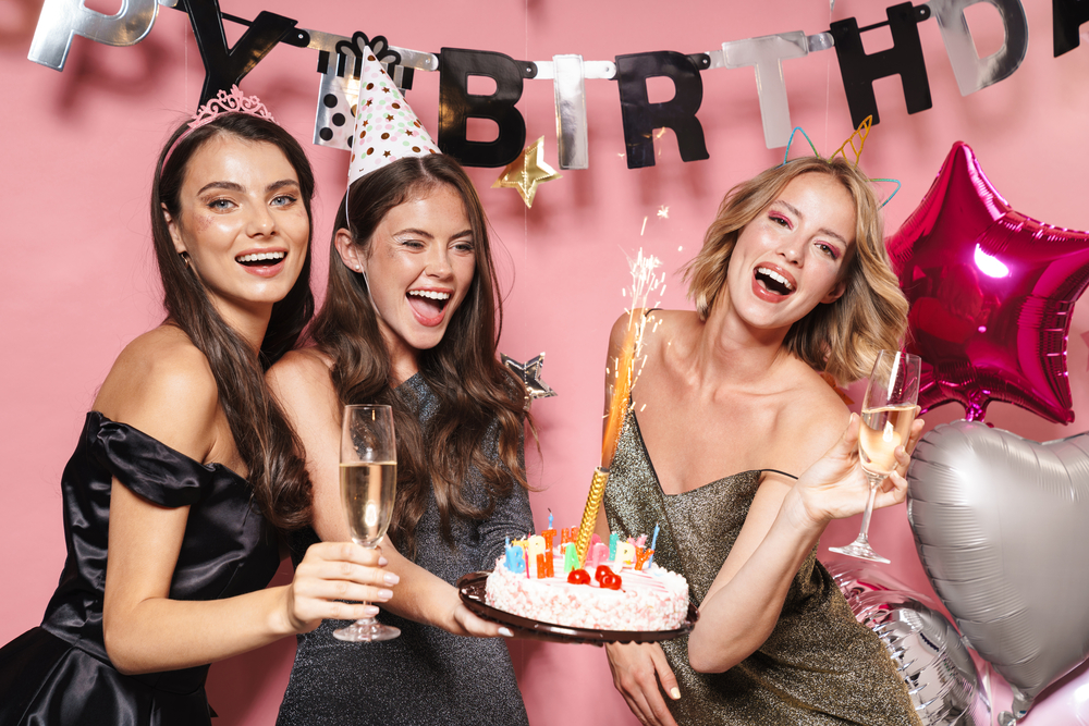 image of joyful party girls holding birthday cake and champagne