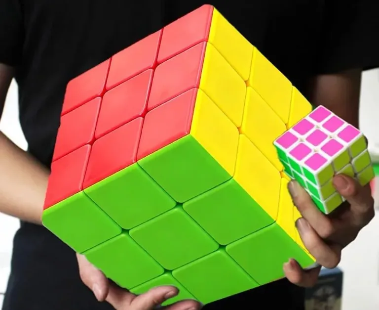 Person holds large and small Rubik's cubes.