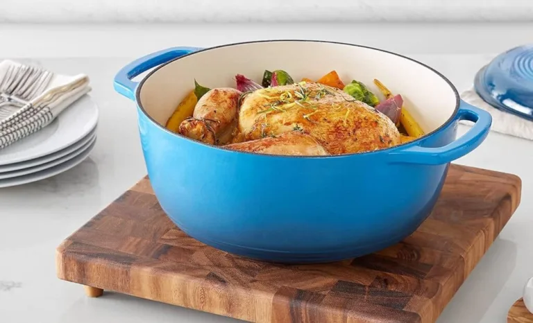 Roast chicken in blue Dutch oven on cutting board.