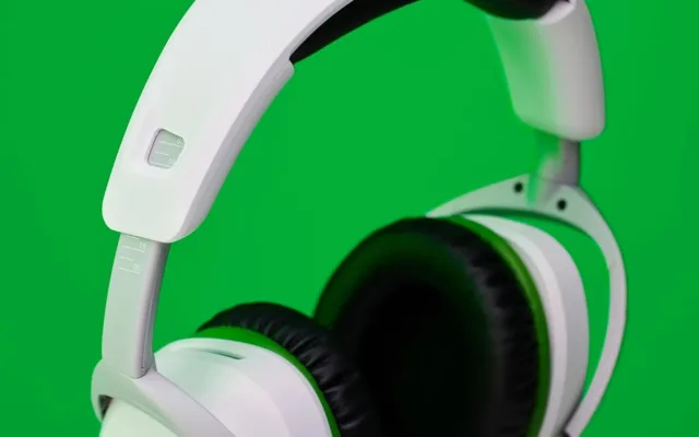White headphones with adjustable custom-fit headband on green.