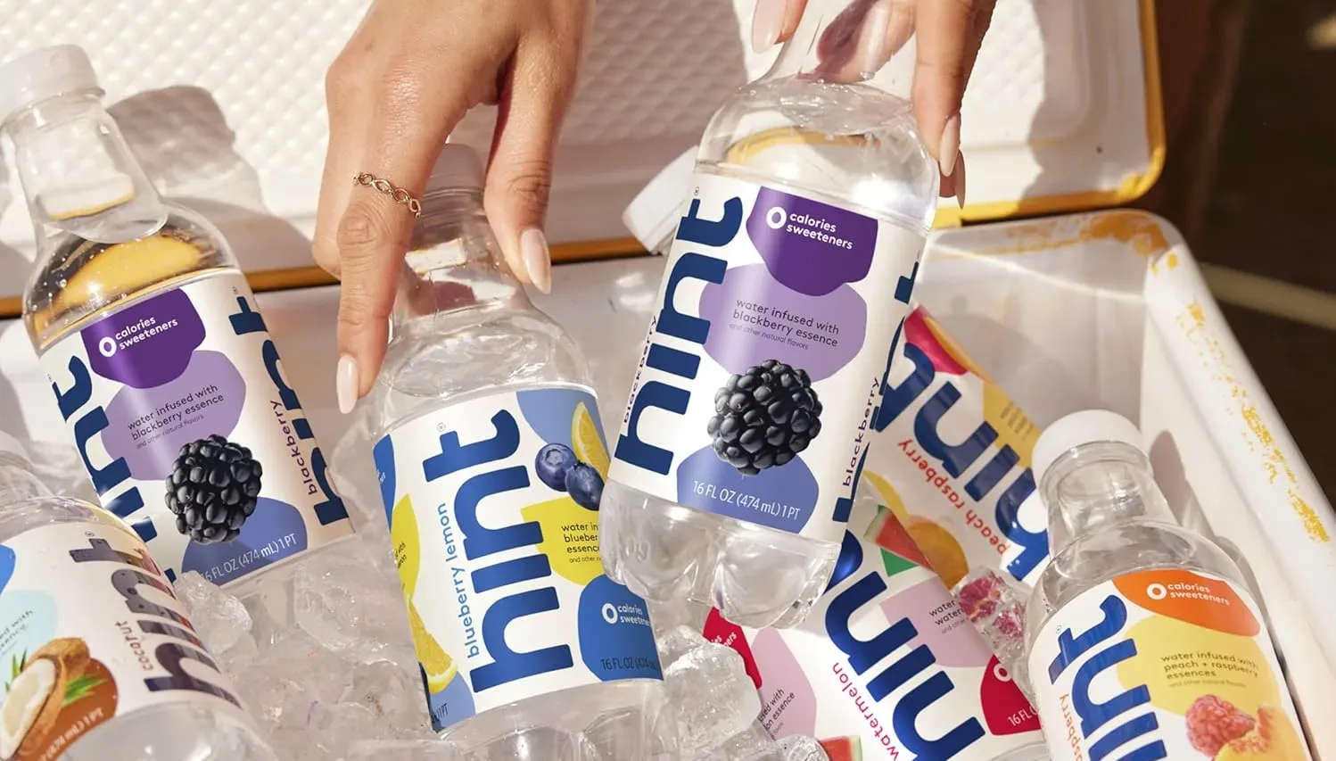 Assorted flavored water bottles on ice in cooler.