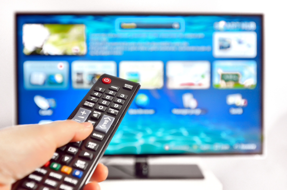 smart tv and hand pressing remote control