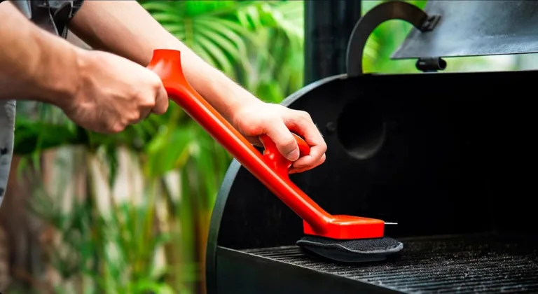 Cleaning barbecue grill with red brush