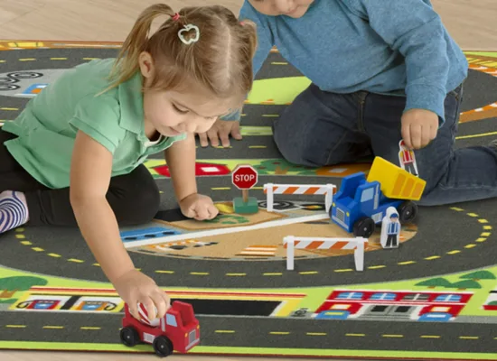 Children playing with toy cars on road rug.