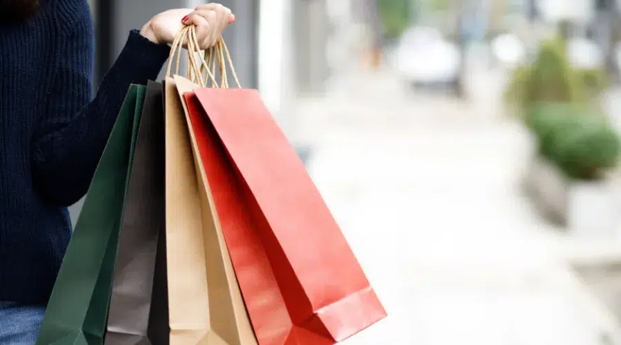 Person holding colorful shopping bags on street.