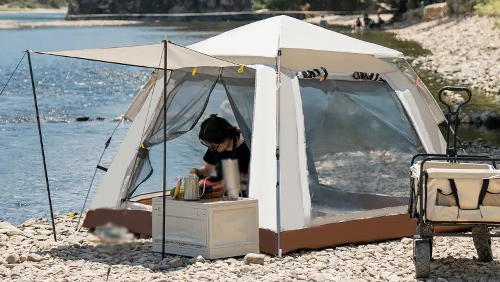 Person cooking inside tent by riverside