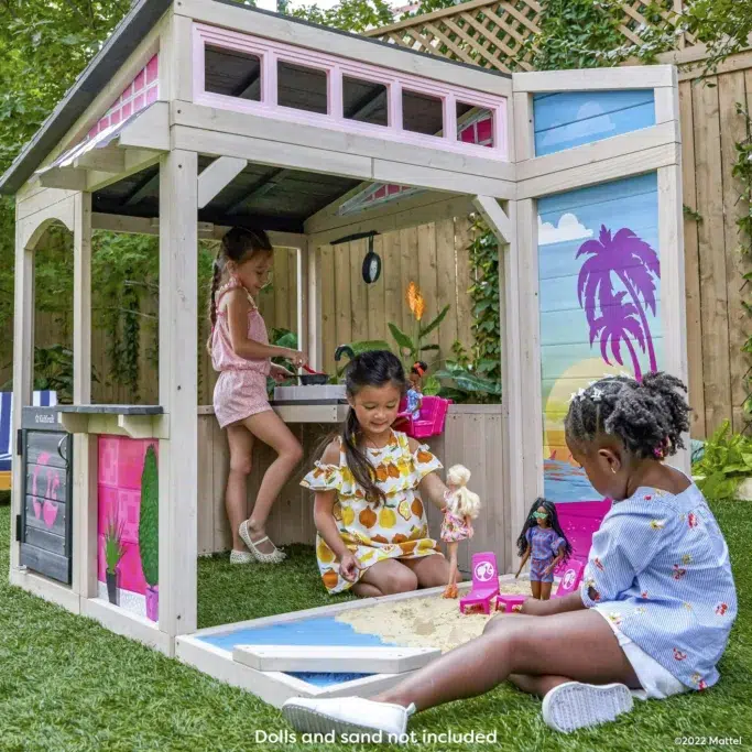 Children playing in outdoor playhouse with sandpit.