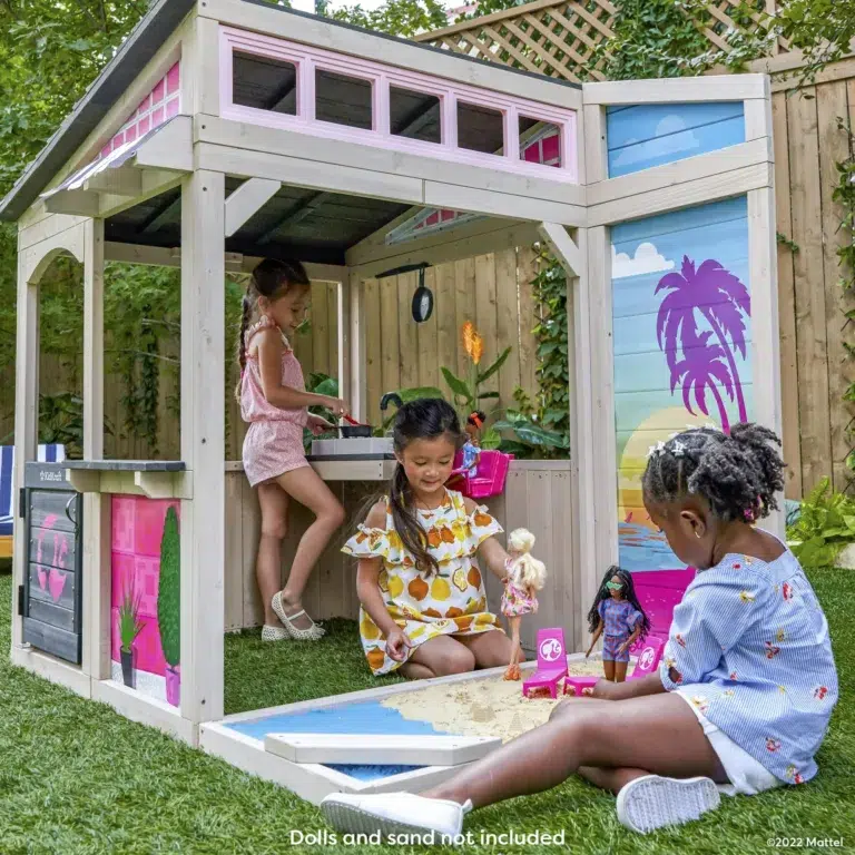 Children playing in outdoor playhouse with sandpit.