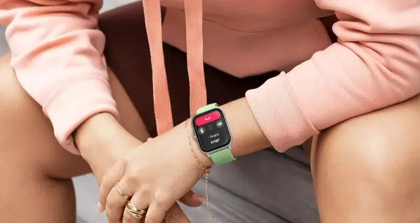 Person wearing smartwatch with green band, casual attire.
