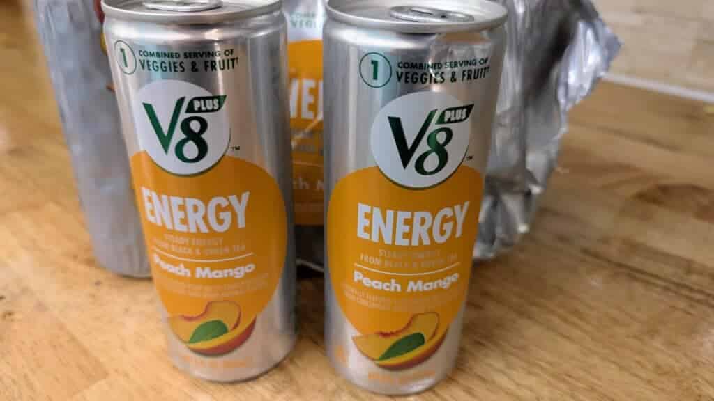 V8 Peach Mango energy drink cans on table.