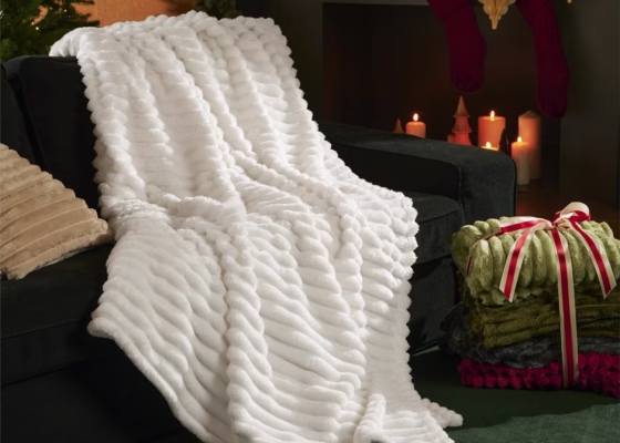 White plush blanket on black sofa, festive setting.