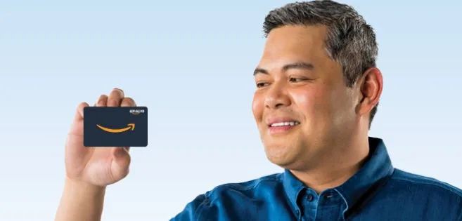 Smiling man holding Amazon gift card.