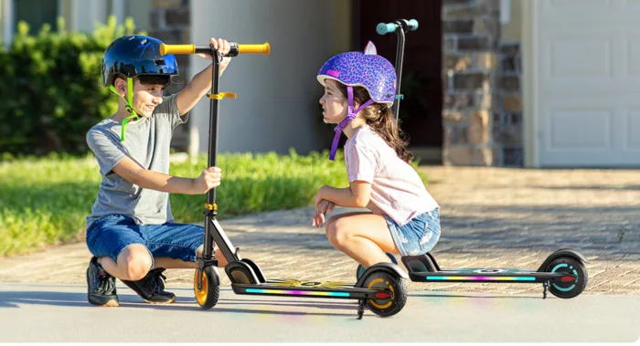 Children enjoying scooter ride wearing helmets.