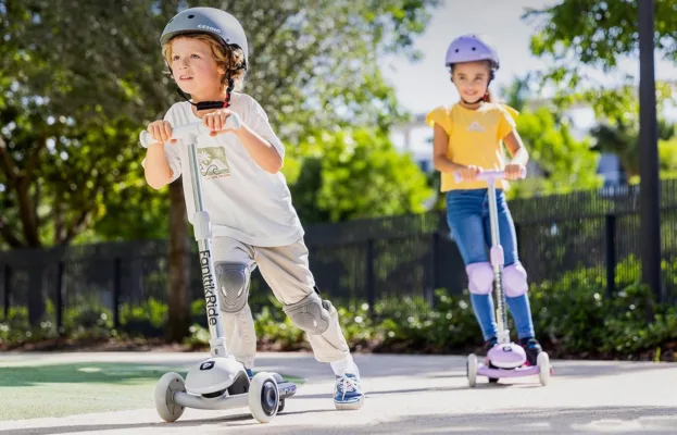 Kids wearing helmets riding scooters in park