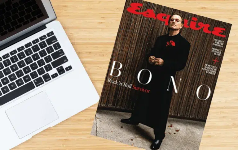 Esquire magazine on wooden desk beside laptop.