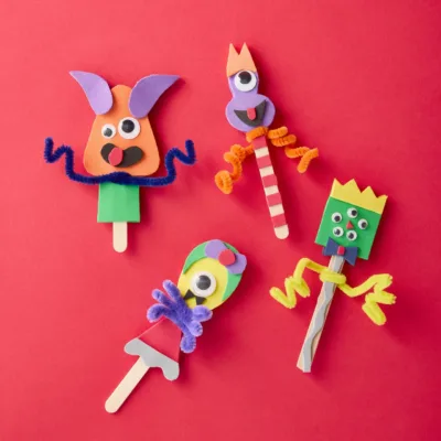 Colorful foam stick puppets on red background.