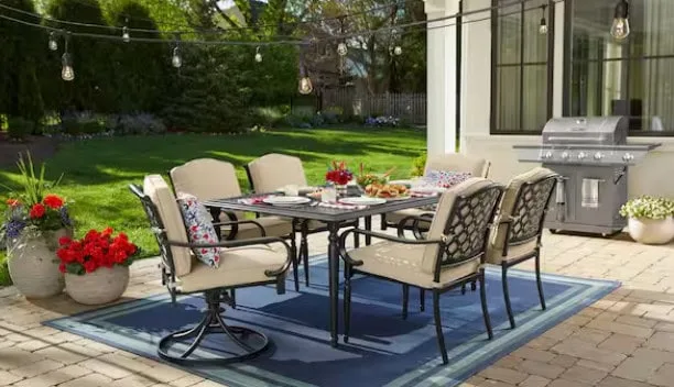 Outdoor patio dining set with grill and flowers.